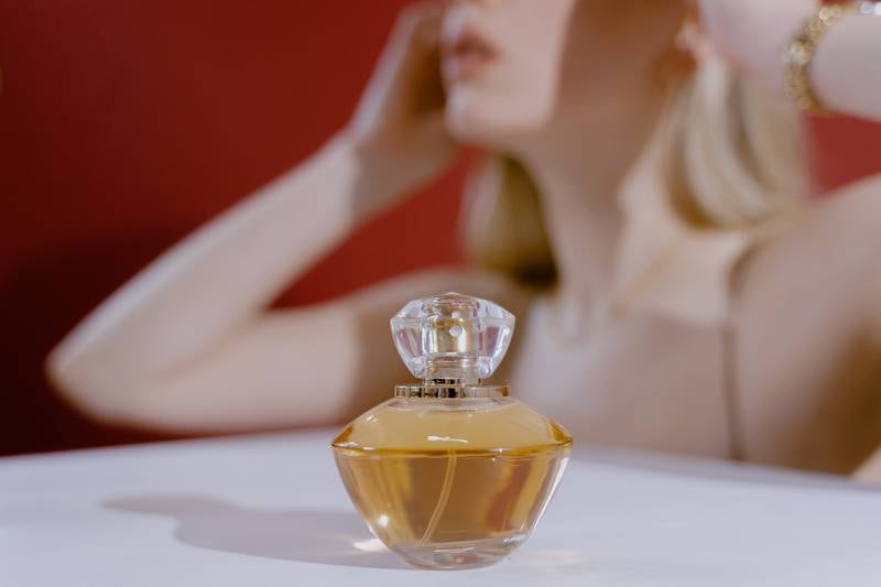 Frasco de perfume com mulher loira atrás