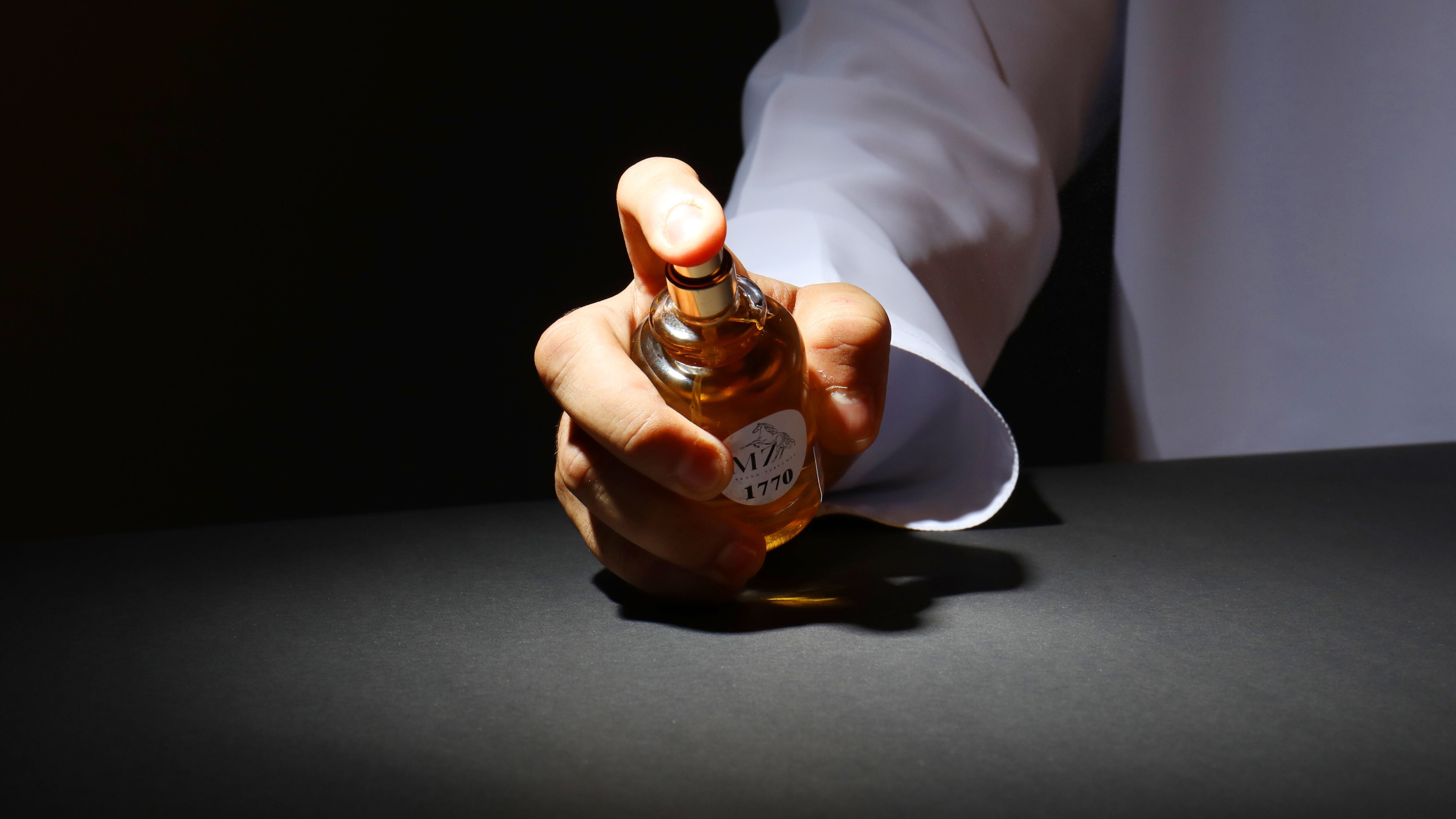 Braço masculino segurando perfume