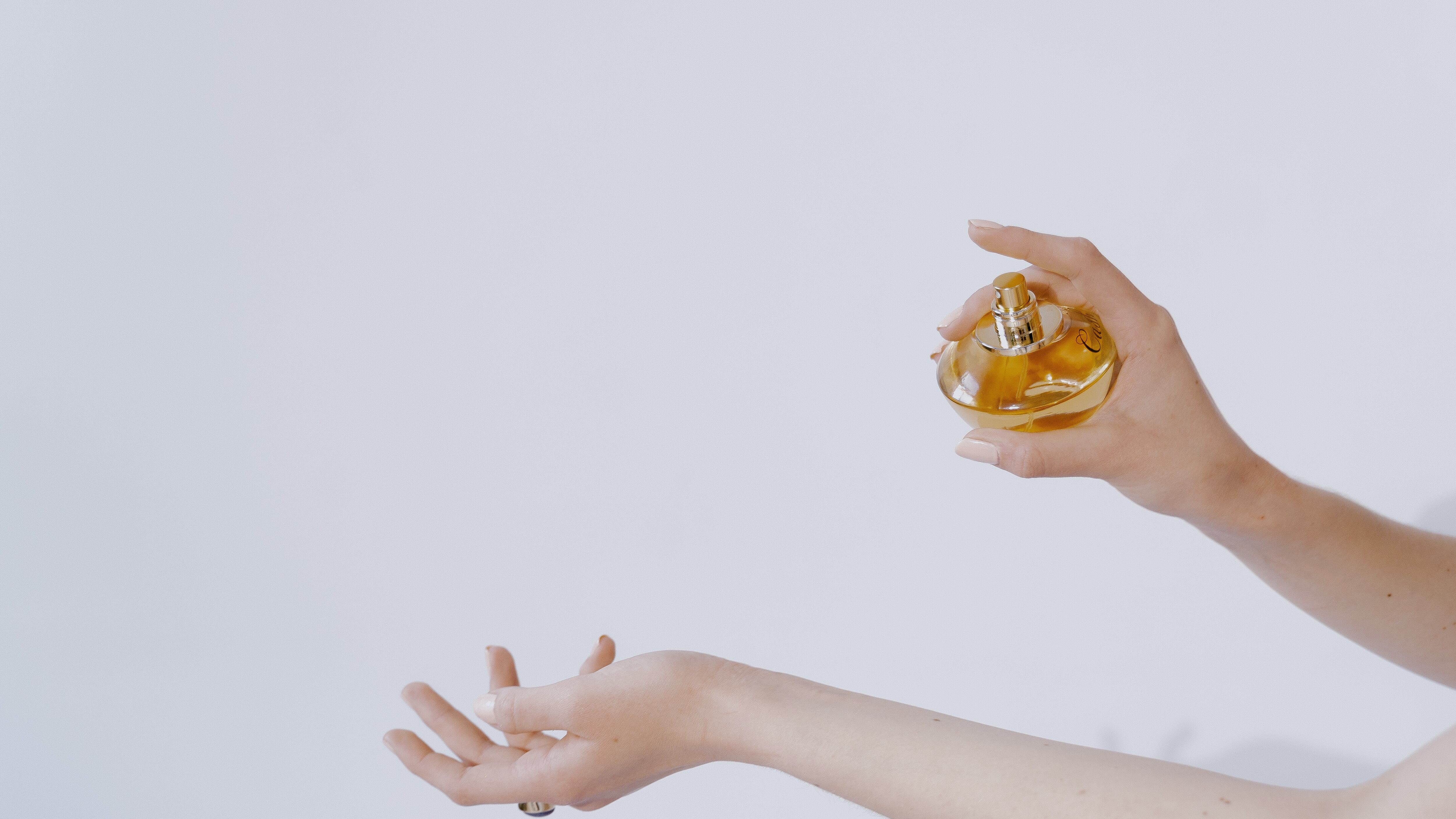 Mulher borrifando perfume no braço