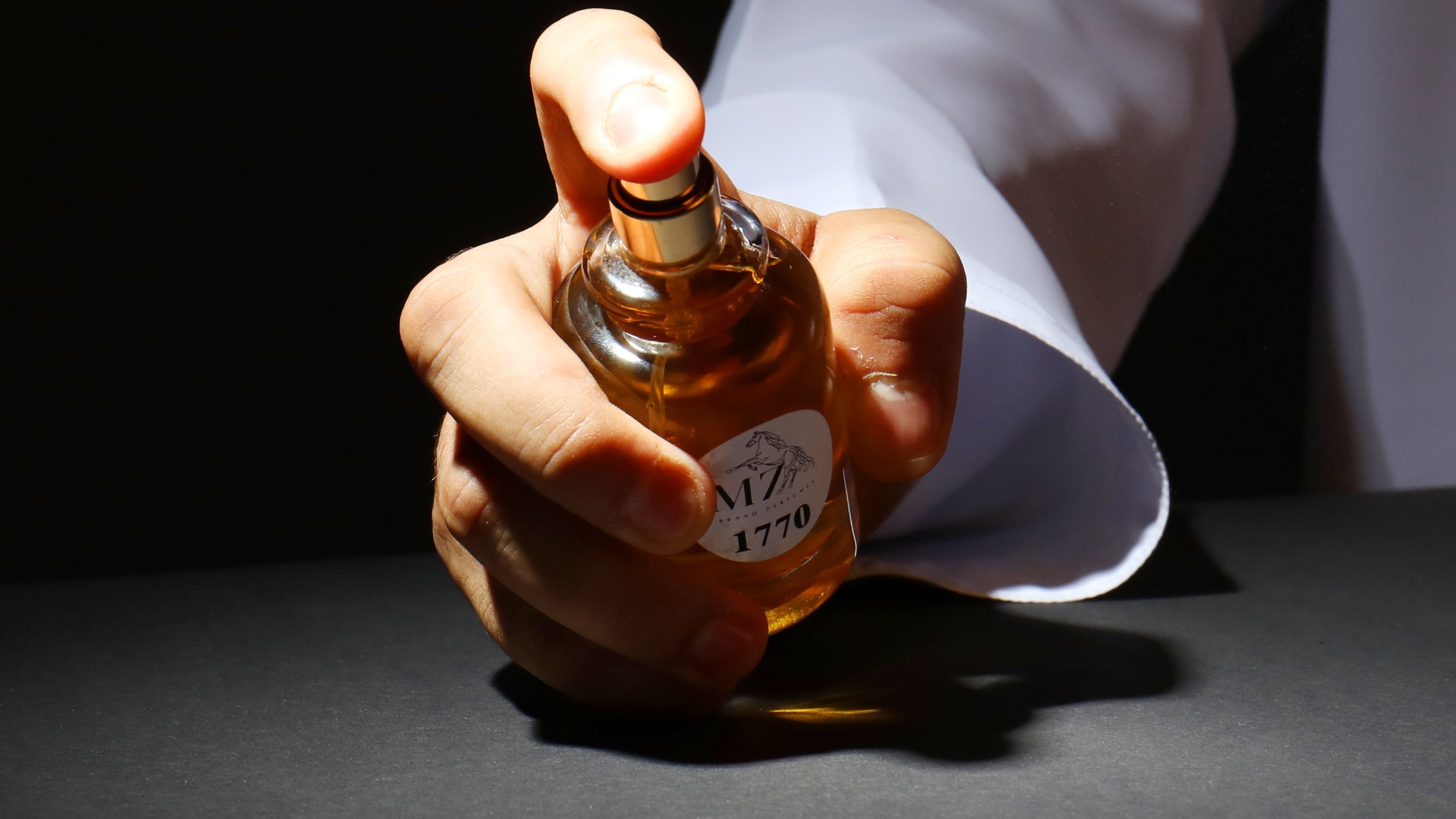 Braço masculino segurando perfume