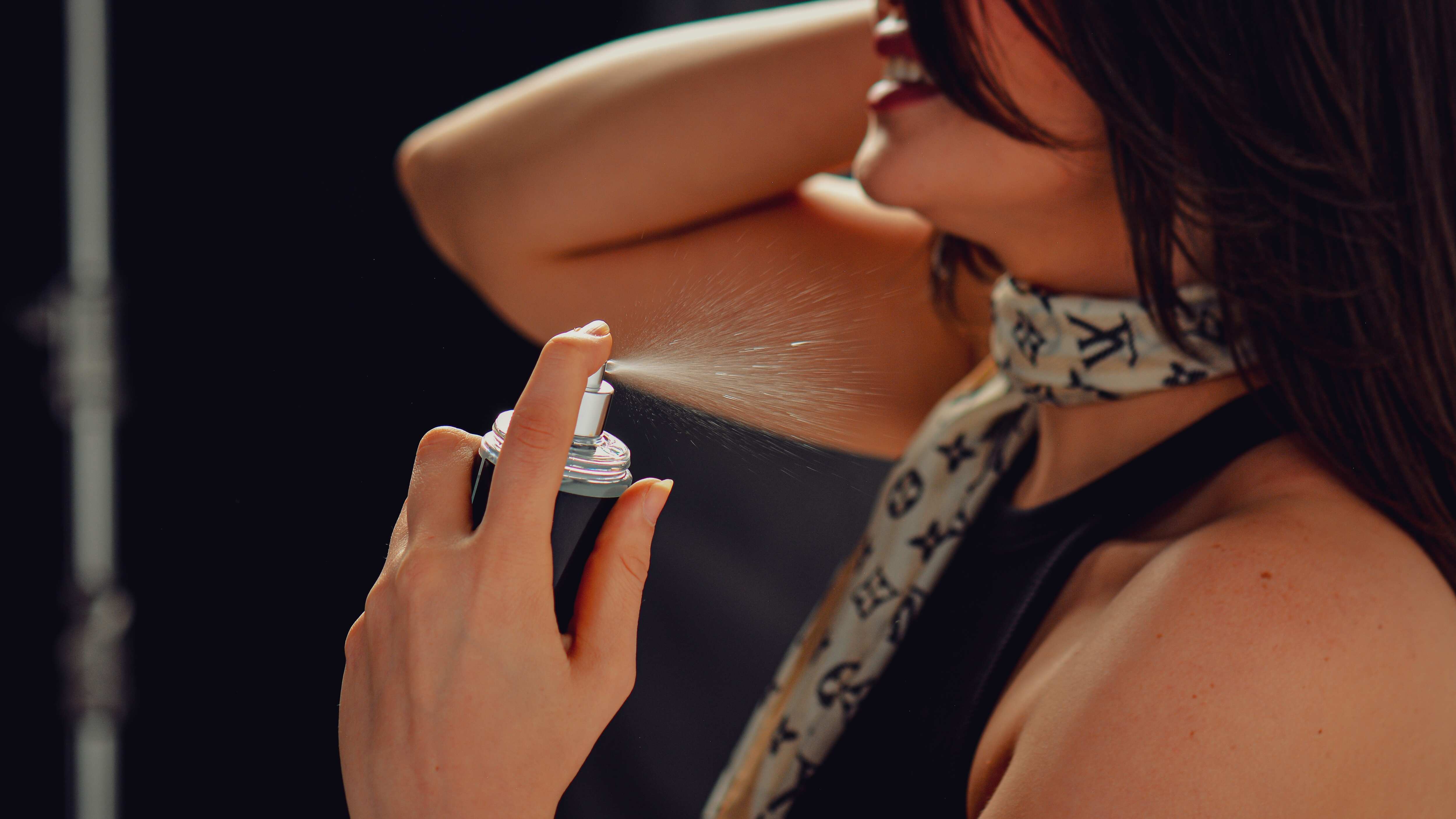 Mulher espirrando perfume no pescoço